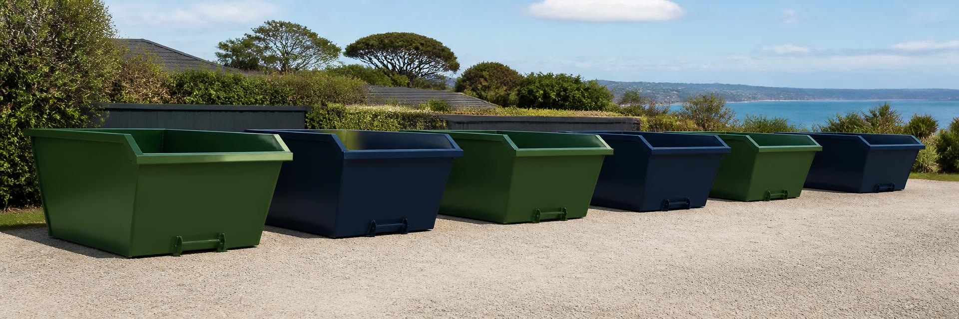 Green and navy Peninsula Skips bins lined up on the Mornington Peninsula